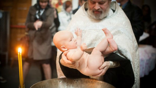 поп крестит ребенка в храме